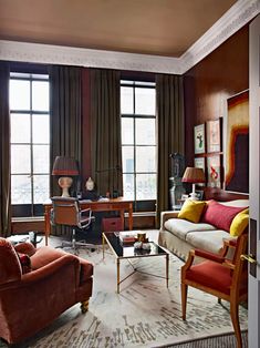 a living room filled with lots of furniture next to large window covered in drapes