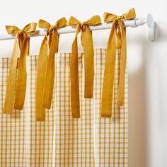 the curtain is hanging on the rod with yellow bows attached to it's sides