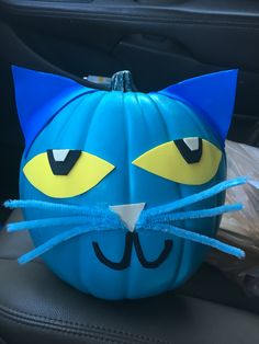 a blue pumpkin decorated like a cat with yellow eyes