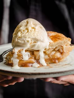 a piece of pie with ice cream on top is being held up by someone's hand