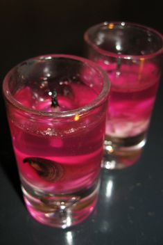 two glasses filled with liquid sitting on top of a white counter next to each other