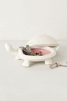 a white turtle shaped jewelry box with a key chain hanging from it's side