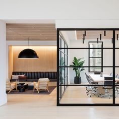 an office with glass walls and wooden flooring is seen from the dining room to the living area