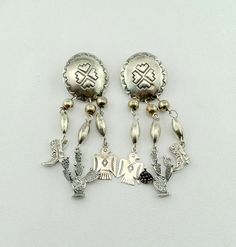 "Vintage Native American sterling silver dangle earrings featuring a concho with three beaded strands. A cowboy boot, cactus, and eagle charm at the end of each strand. Unmarked as was typical before 1970. A wonderful addition to your personal jewelry collection. FREE Domestic Shipping!! Details: Sterling Silver (as shown in picture) Approximate Dimensions: 3 1/2 inches x 1 inch Total Weight (together): 30.5 grams FREE domestic shipping by USPS Priority Mail delivery confirmation and includes in Silver Concho Earrings As A Gift, Silver Concho Earrings For Gift, Decorative Silver Earrings As Gift, Concho Dangle Earrings For Gift, Silver Teardrop Concho Earrings, Silver Concho Drop Earrings, Silver Concho Dangle Earrings, Silver Dangle Earrings With Concho, Jewellers Bench