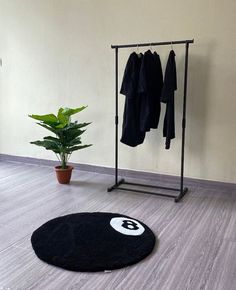 a coat rack and potted plant on the floor in front of a white wall