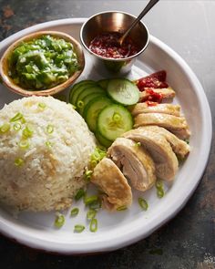 a white plate topped with rice, meat and veggies next to dipping sauce