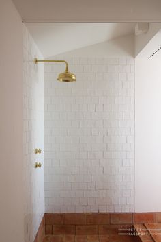 a bathroom with white brick walls and a gold faucet in the shower head