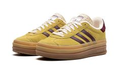 The Women’s adidas Gazelle Bold “Yellow/Burgundy” is a women’s-exclusive colorway of the retro shoe with a platform-style sole and other modifications.  The contemporary-looking adidas Gazelle Bold features a triple-stacked, raised sole.  As for the rest of the design, the shoe features a mustard yellow suede upper with burgundy leather Three Stripes on the sides.  Gold “Gazelle” branding is seen on the lateral side of the shoe.  The burgundy terry cloth heel tab matches the material used on the shoe’s inner lining.  A stacked gum rubber sole completes the look. Adidas Gazelle Platform, Gazelle Platform, Adidas Shoes Gazelle, Adidas Gazelle Bold, Gazelle Bold, Adidas Three Stripes, Burgundy Shoes, Yellow Shoes, Stadium Goods