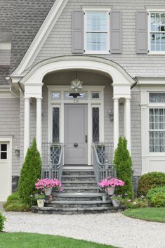 the front entrance of a house with steps leading up to it and flowers in pots