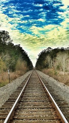 a train track with trees and sky in the background