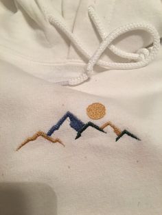 Machine embroidered mountain hoodie Heavy Blend, soft, comfortable. Pullover Embroidery Ideas, Mountain Embroidery Hoodie, Sporty Hoodie With Embroidered Graphics For Winter, Embroider Mountains, White Hoodie With Custom Embroidery For Winter, Custom Embroidered Hoodie For Winter, Custom Embroidered Winter Hoodie, White Cotton Sweater For Outdoor, Winter Hoodie With Custom Embroidery