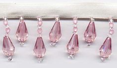 six pink glass beads are lined up on a white cloth with a zippered pouch behind them