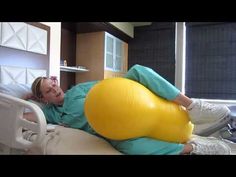 a woman laying on top of a yellow ball in a hospital bed