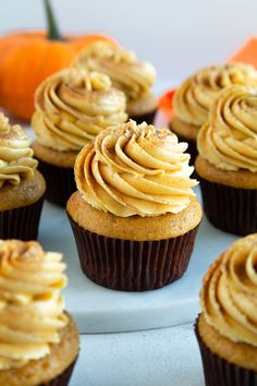 cupcakes with frosting and pumpkins in the background on a plate,