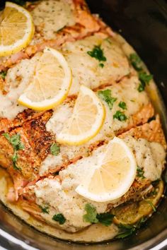 fish with lemons and parsley in a crockpot, ready to be cooked