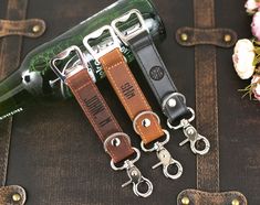 three leather keychains are sitting next to a bottle