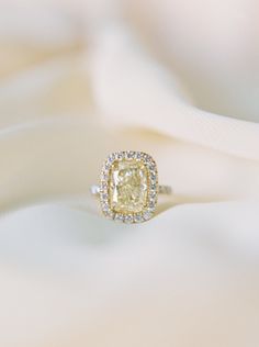 a yellow diamond ring sitting on top of a white cloth