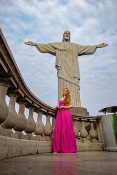 a woman standing in front of the statue of christ