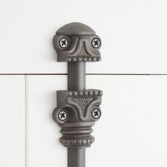 an iron door handle on the side of a white painted cabinet with black knobs