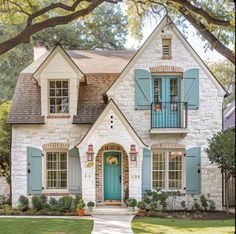 a white brick house with blue shutters on the front door and green shutters