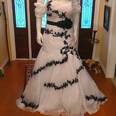 a white and black wedding dress on display in front of a door with stained glass windows