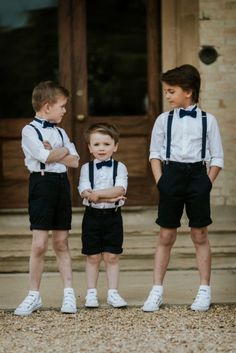 three young boys wearing black shorts and bow ties standing in front of a door with their arms crossed