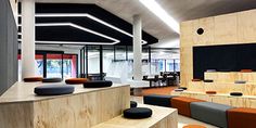 the interior of a modern office building with wood and black accents, including orange seats