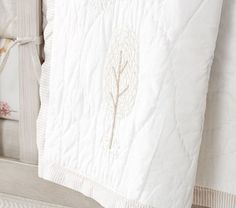 a white quilt hanging from the side of a bed