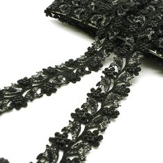 a close up of a black lace with flowers on it and a cell phone in the background