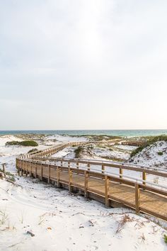 a wooden walkway leads to the beach on a cloudy day with no people around it