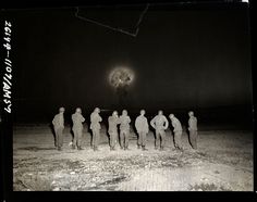 a group of people standing in the snow at night with an object in the background