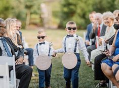 two young boys are walking down the aisle at a wedding with their parents and grandparents