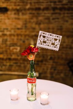 a bottle with a flower in it sitting on top of a table