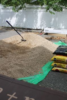 a pile of dirt sitting on top of a parking lot next to a shovel and bag