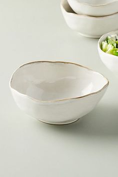 three white bowls filled with lettuce on top of a table