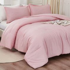 a bed with pink comforter and pillows on it