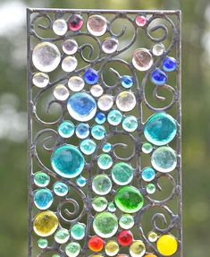 a colorful stained glass panel with swirls and circles on it's side, hanging from a metal rod