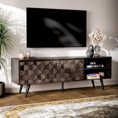 a living room with a large flat screen tv on the wall and a plant next to it