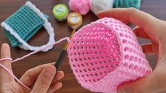 someone is crocheting a pink hat on a table with other crafting supplies