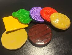 four different colored candies sitting on top of a black table next to each other