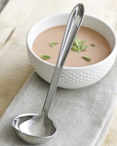 a white bowl filled with soup and two spoons on top of a cloth napkin