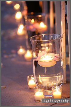 candles are lit in glass vases on the ground