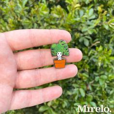 a hand holding a small green plant with a skull on it