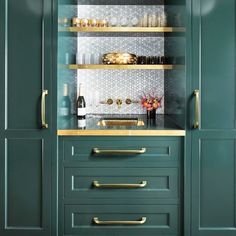 a kitchen with green cabinets and gold handles