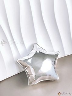 a silver star shaped dish sitting on top of a table next to a white wall