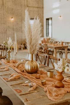 the table is set with candles, vases and other decorative items for an autumn wedding