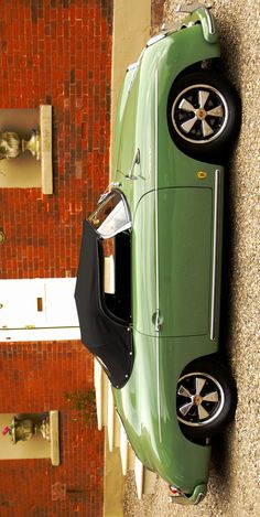 an overhead view of a green car parked on the side of a brick building with its door open