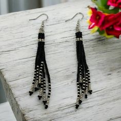 These fringe earrings in black and silver are the perfect blend of boho style and wearable art, featuring long tassels that make a bold statement. A thoughtful gift idea for your daughter, these neutral shade dangle earrings add a touch of fashion-forward elegance to any outfit. ABOUT * Beaded earrings * Fringe/ Tassel style * Measurements: -Height: approximately 4 inches -Width: approximately 1/2 inch  It is recommended that these earrings are stored laying flat or hanging up.  If you like this Adjustable Silver Tassel Earrings For Party, Elegant Black Earrings With Silver Beads, Black Earrings With Silver Beads As Gift, Black Dangle Jewelry For Festival, Black Dangle Jewelry For Festivals, Black Bohemian Drop Earrings, Bohemian Black Earrings With Silver Beads, Adjustable Silver Beaded Earrings With Black Beads, Adjustable Black Beaded Earrings For Festival