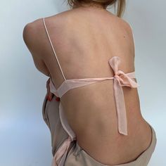 the back of a woman's body with a pink ribbon tied around her waist