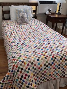 a teddy bear sitting on top of a bed in a room with wood flooring